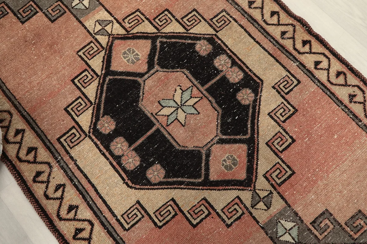 Close-up of a black geometric medallion with a star motif and surrounding beige and gray patterns.