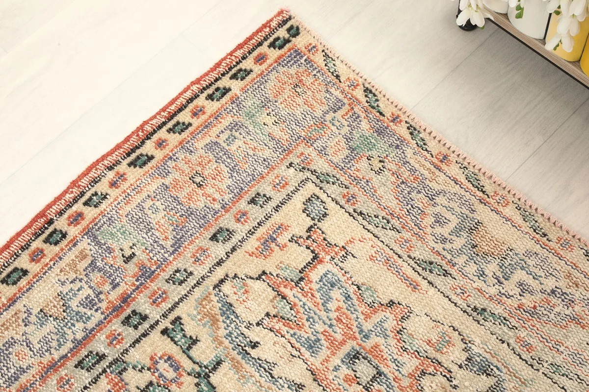 Close-up of the rug's border, highlighting geometric and floral motifs in blue, orange, and beige