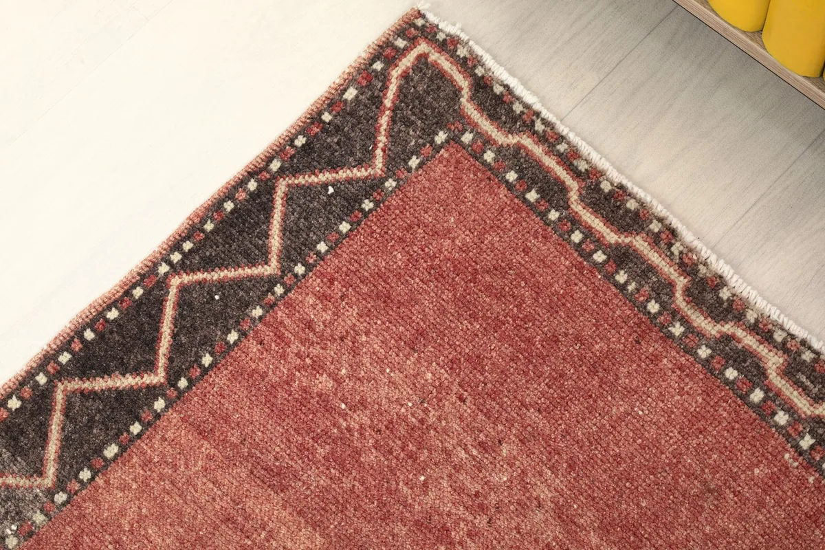 Corner view of the rust runner rug, showing the border and field texture.