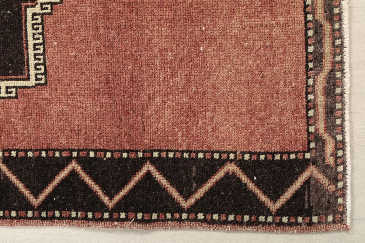 Detail of the rust runner's charcoal border with a zigzag pattern and the main field.