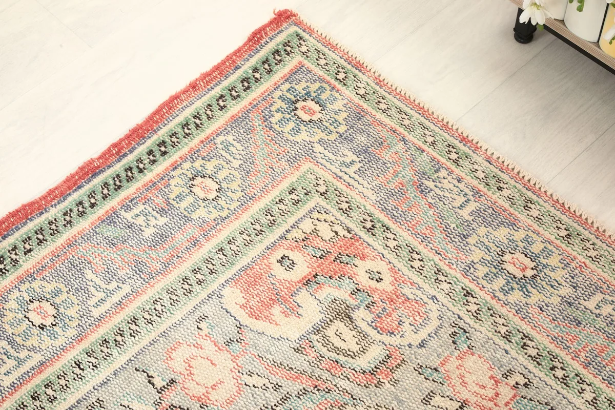 Detailed shot of the rug's corner, emphasizing the intricate patterns in the blue and green borders