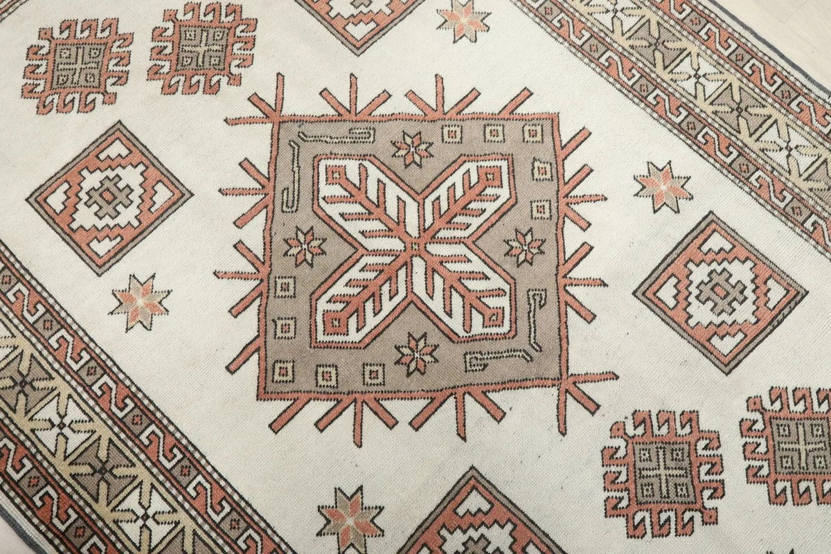 Close-up of the central geometric medallion and surrounding tribal motifs on the ivory rug.