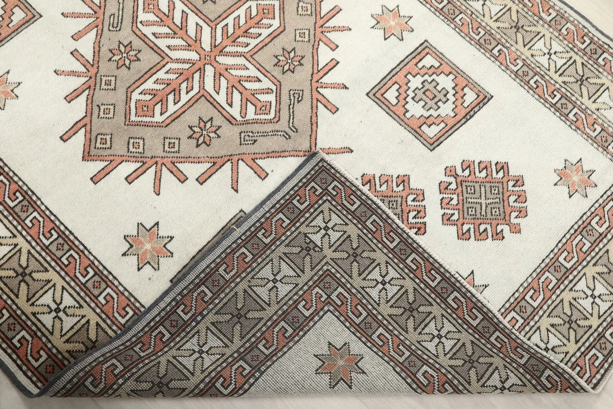 Corner of the rug folded back, revealing the reverse side and the cotton foundation.