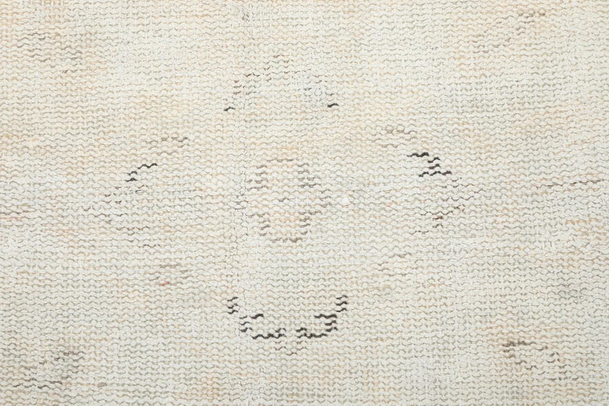 Macro detail of the hand-knotted wool pile showing a central faded medallion-like motif