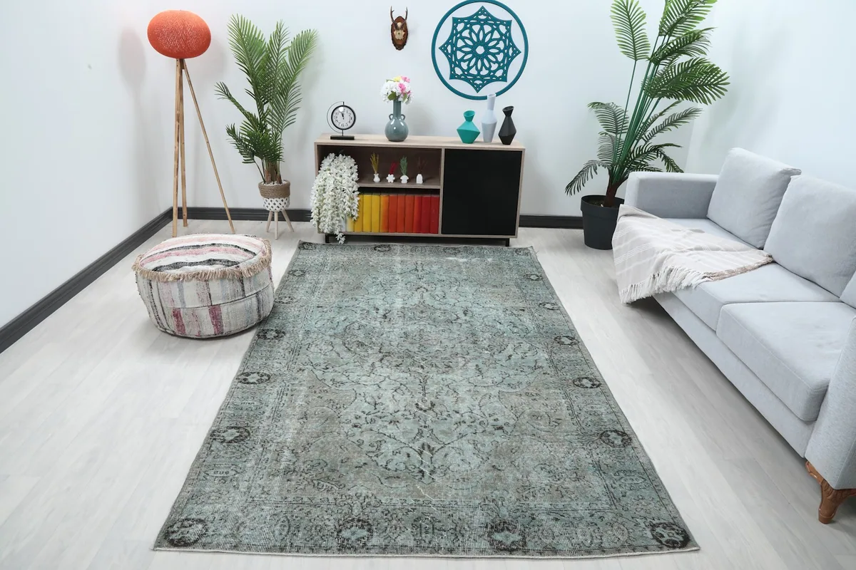 Blue and gray vintage Anatolian rug displayed in a modern living room setting with a light sofa