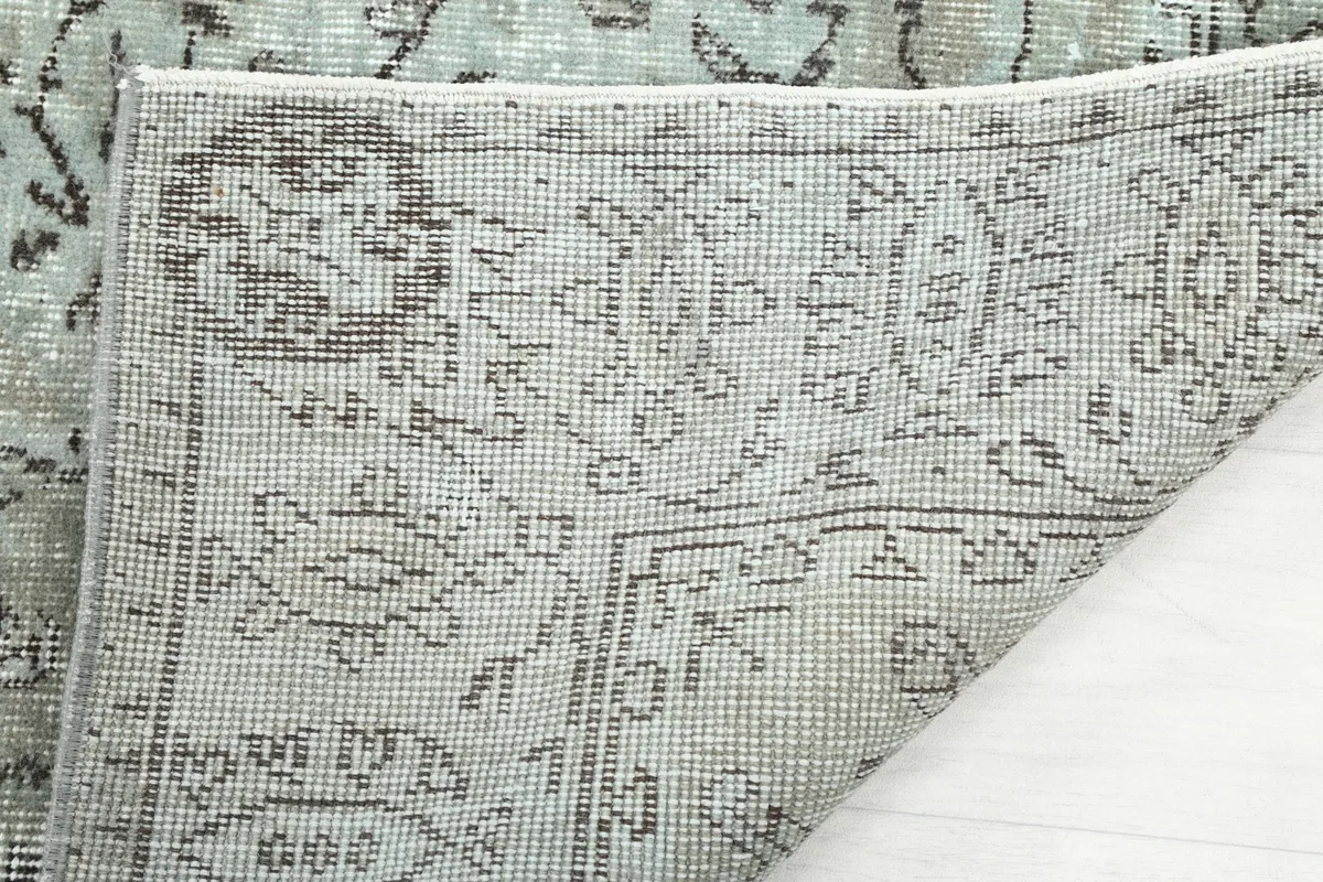Underside view of the rug's folded corner, showing the hand-knotted construction and foundation