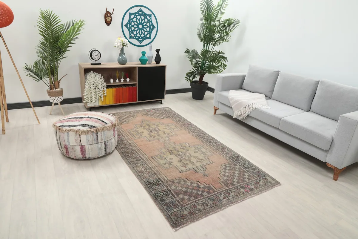 Angle view of the rose and olive vintage rug in a living space, showing its placement relative to furniture