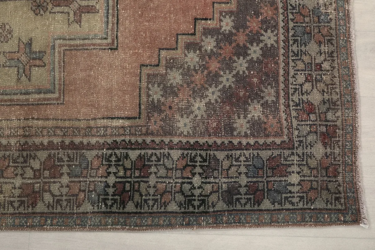 Detail of the rug's gray border with intricate tribal motifs and a corner of the rose field