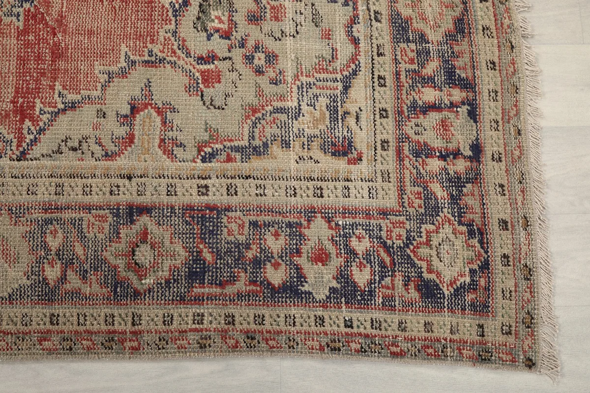 Detail of the rug's corner, showing the navy and beige border patterns and natural fringe