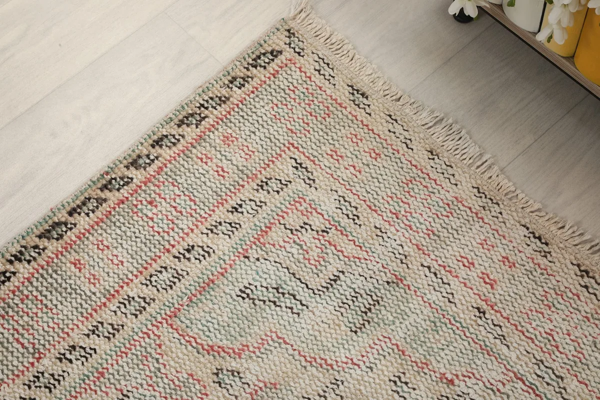 Corner detail of the rug, focusing on the intricate border design and fringe texture