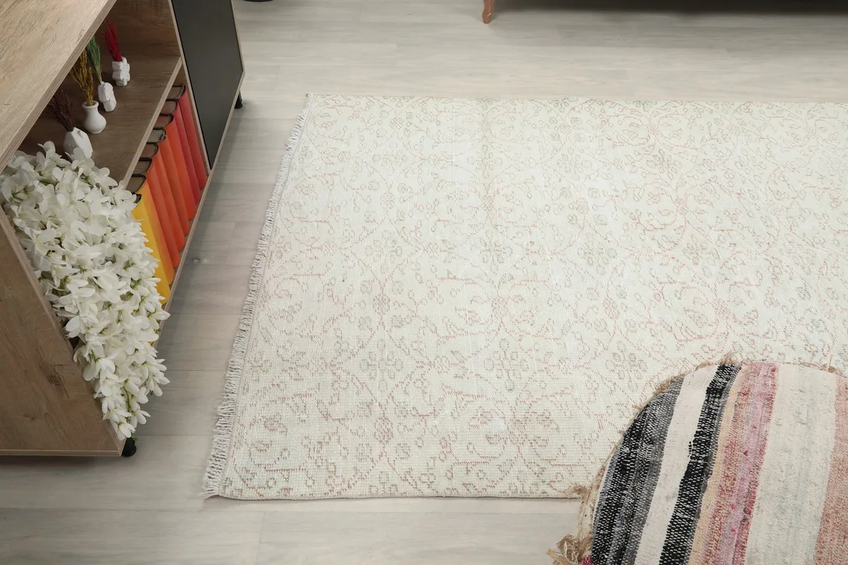 Corner view of the rug next to a decorative pouf and a cabinet, highlighting the rug's proportions