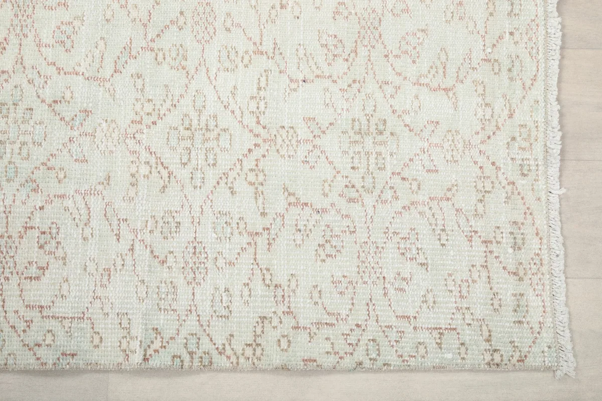 Detailed view of the rug's edge, highlighting the hand-knotted wool pile and faded rose motifs