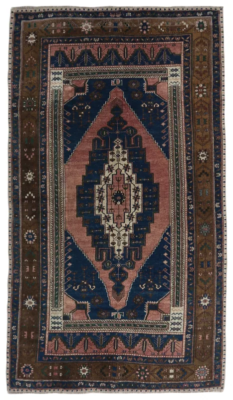 Full overhead view of a vintage rose, navy, and brown geometric medallion rug on a white background.