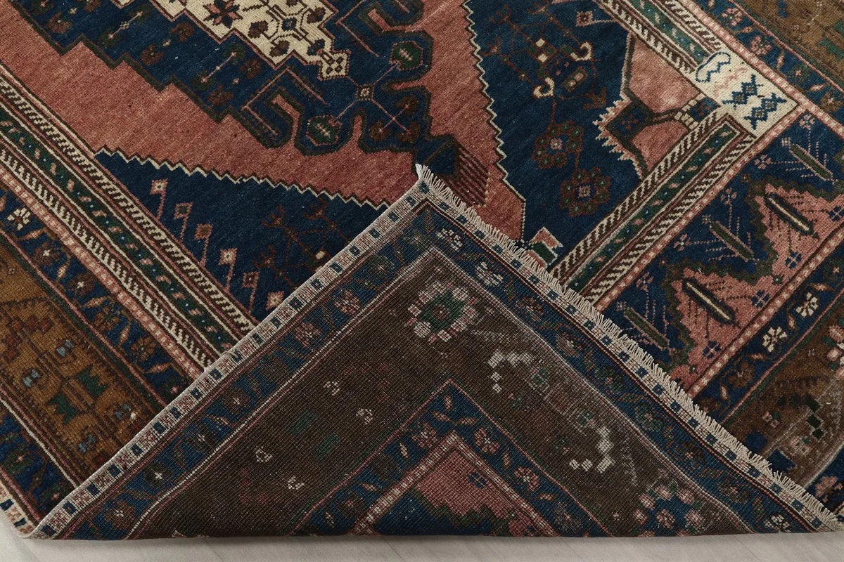 Folded corner of the rug, revealing the back of the hand-knotted wool pile and cotton foundation.