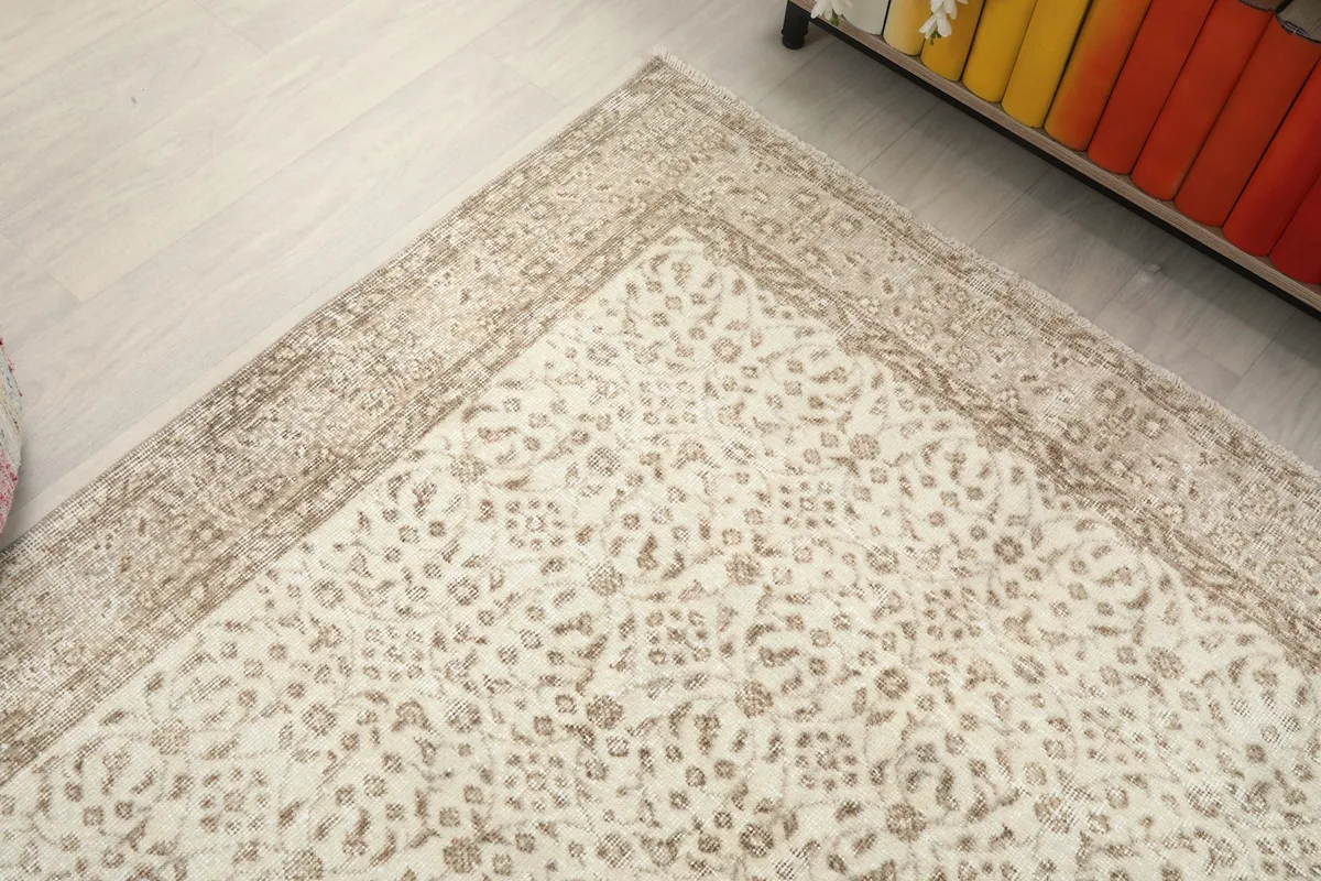 Top-down angle of the rug's corner, emphasizing the intricate floral motifs and the faded tan border