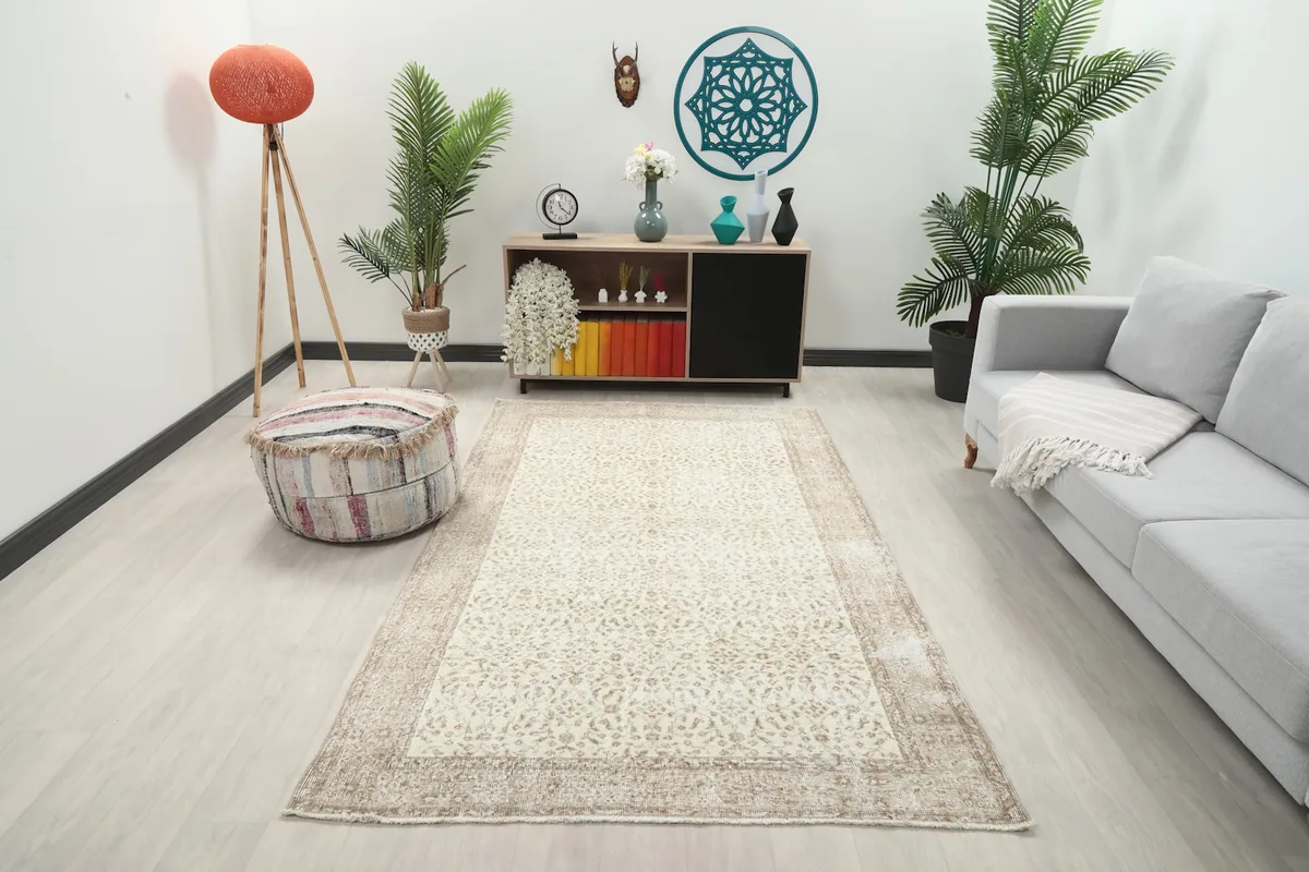 Vintage Anatolian rug displayed in a living room setting with a light gray couch and wooden furniture