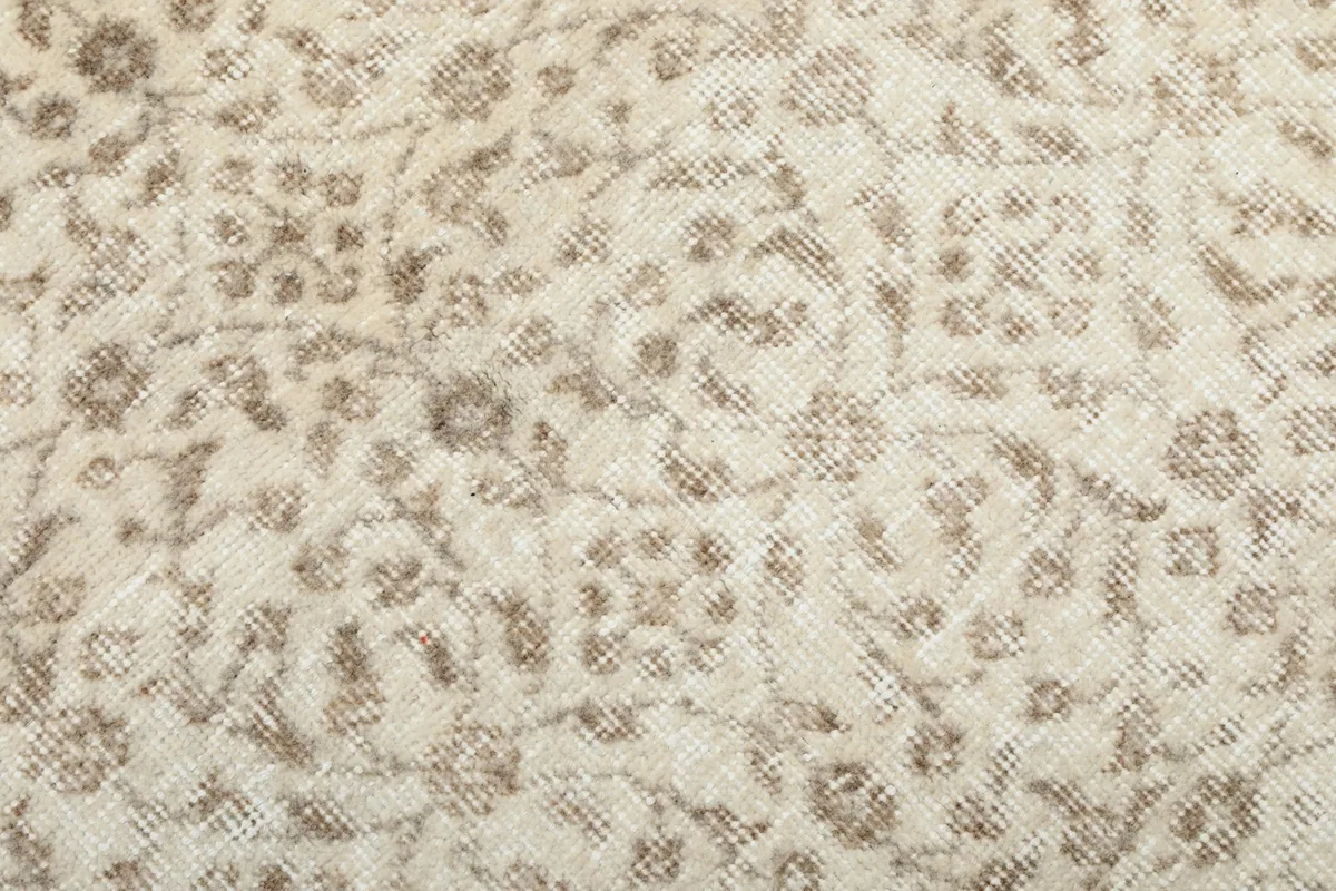 Close-up of the low wool pile, revealing the hand-knotted texture and delicate ivory and tan patterns