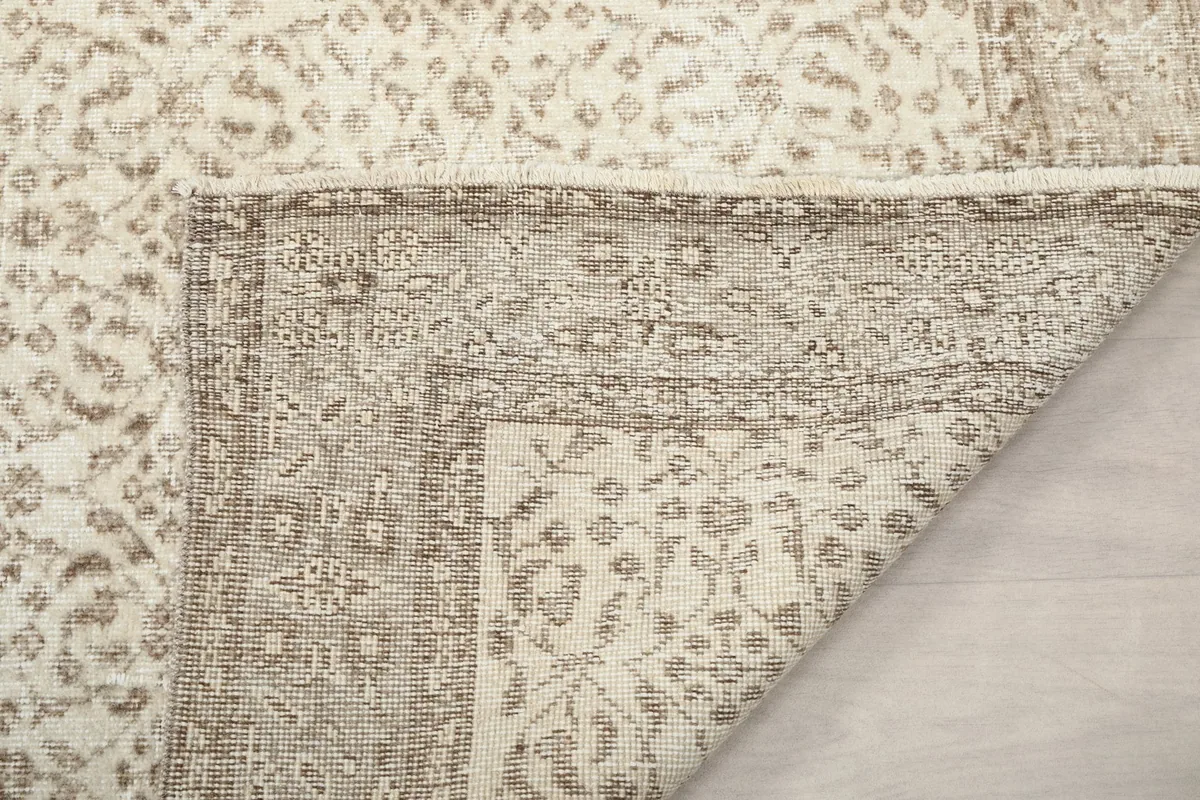 Underside of the rug visible from a folded corner, revealing the cotton foundation and hand-knotted construction