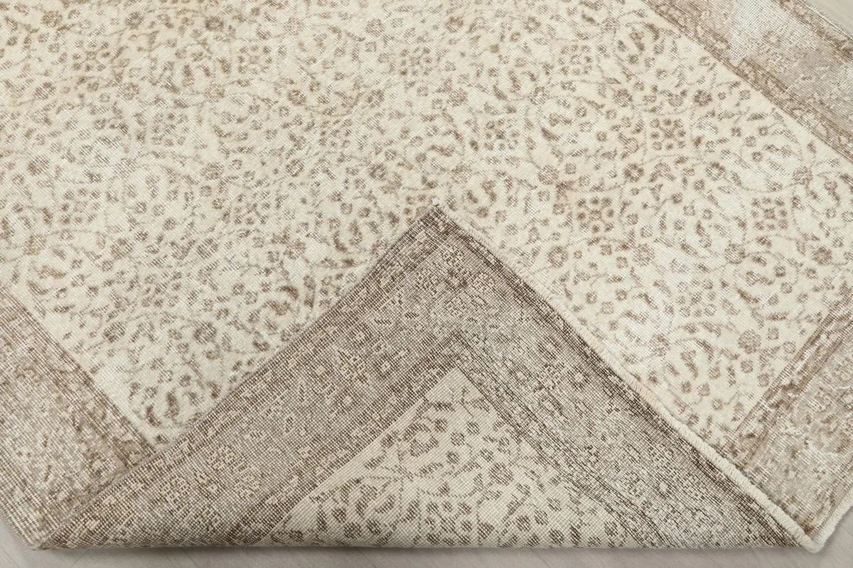 Corner of the rug folded back, showing the consistent pattern and backing