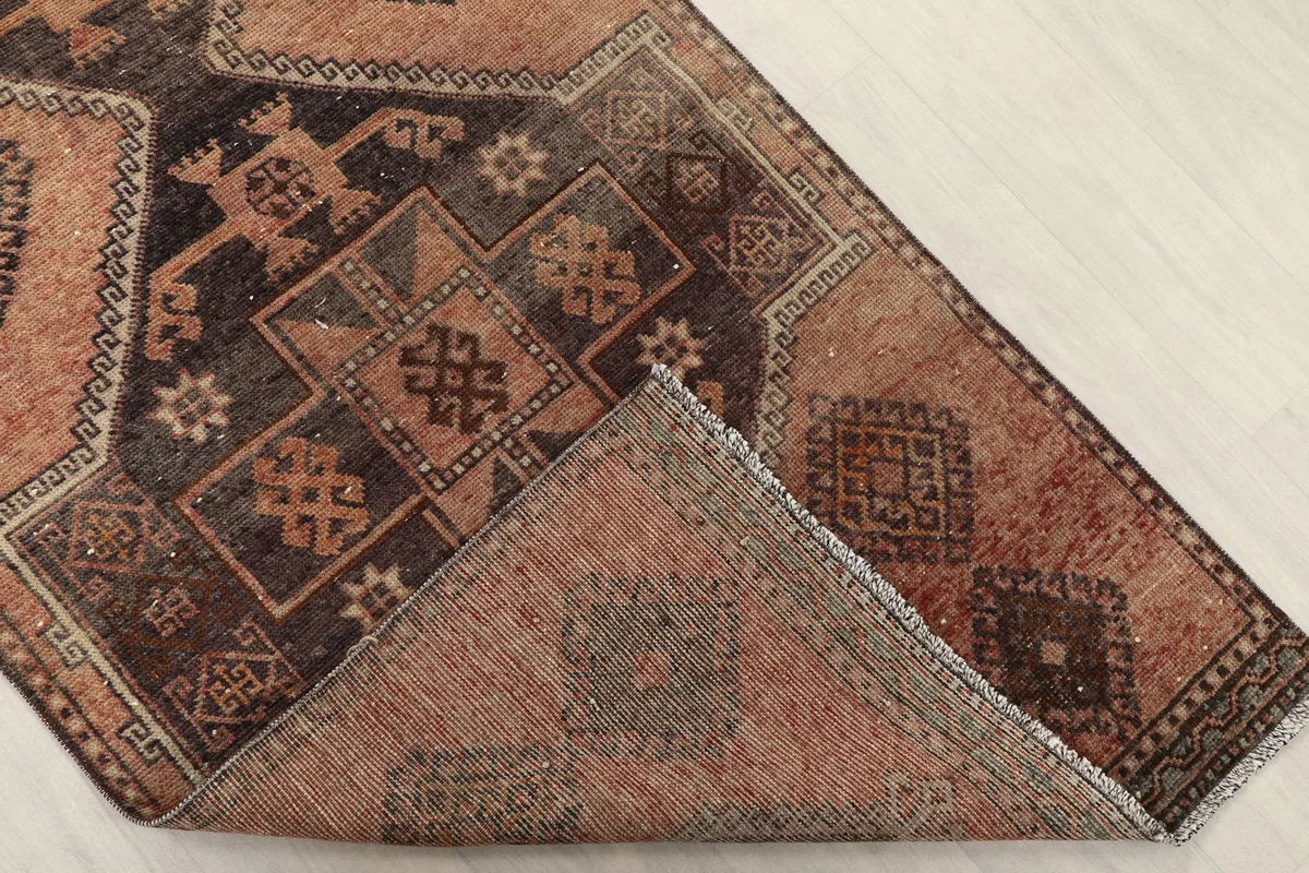 Corner of the runner rug folded back to show the wool pile and cotton foundation construction from the front.