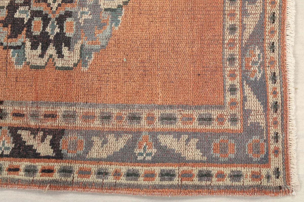 Detailed shot of the rust runner rug's corner, showing the navy and beige geometric border design.