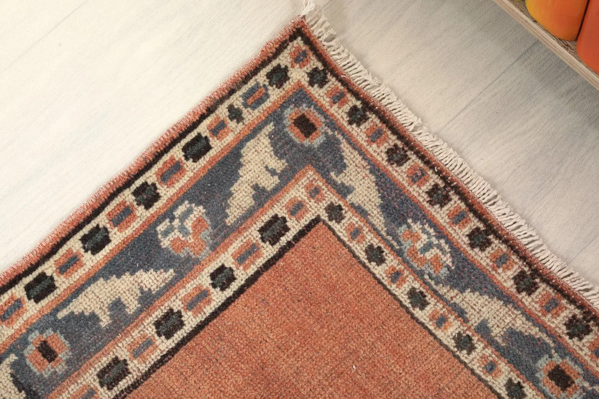Detailed corner of the rust runner rug, showcasing the intricate navy, beige, and rust border patterns.