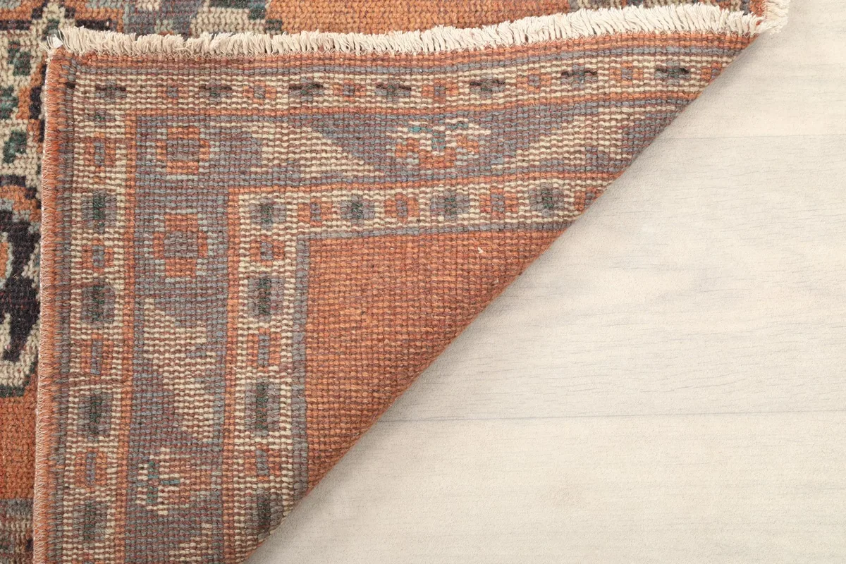 Underside view of the rust runner rug, showing the hand-knotted construction and cotton foundation.