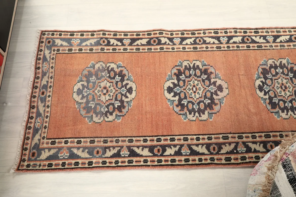 Overhead view of a section of the rust runner rug, displaying its medallions and borders from above.