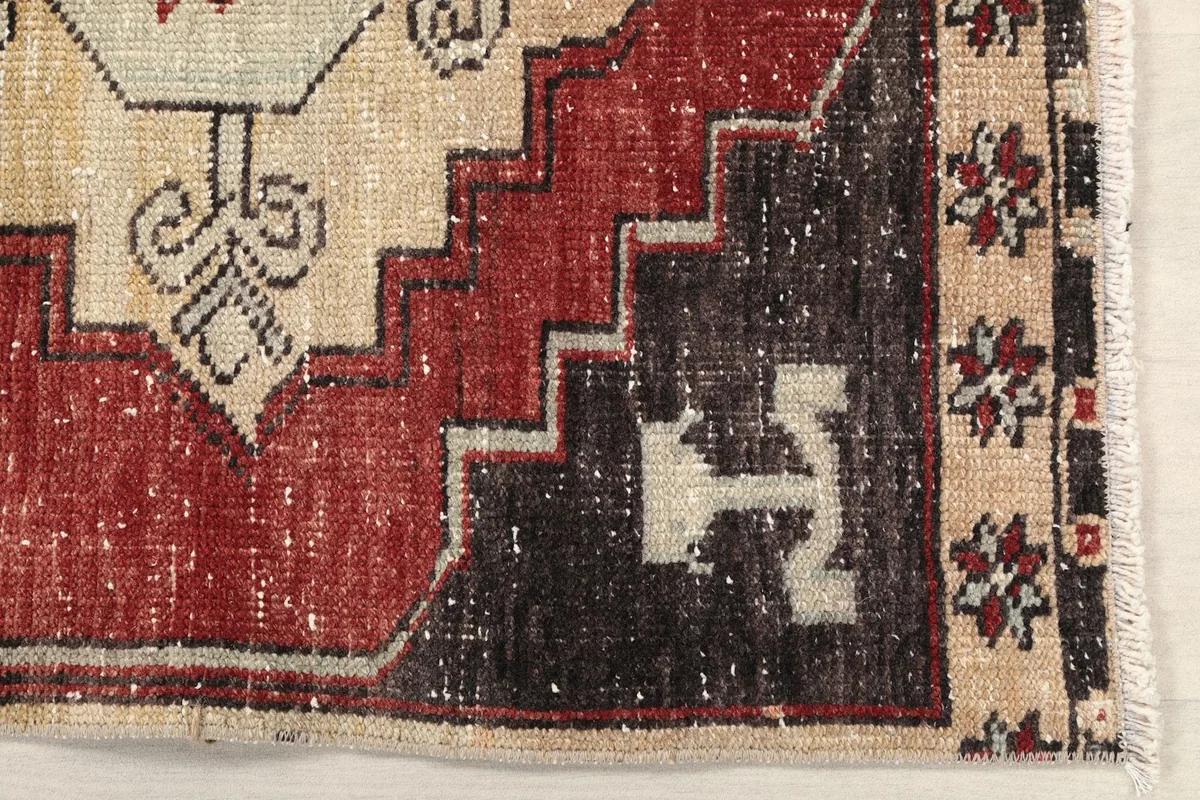 Detailed view of the rug's lower left corner, showing tribal motifs and color variations.