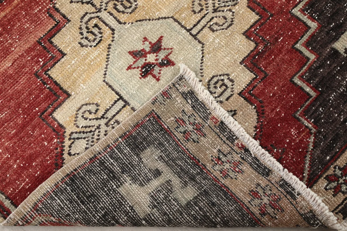 Corner of the rug folded back to show the hand-knotted cotton foundation and wool pile.