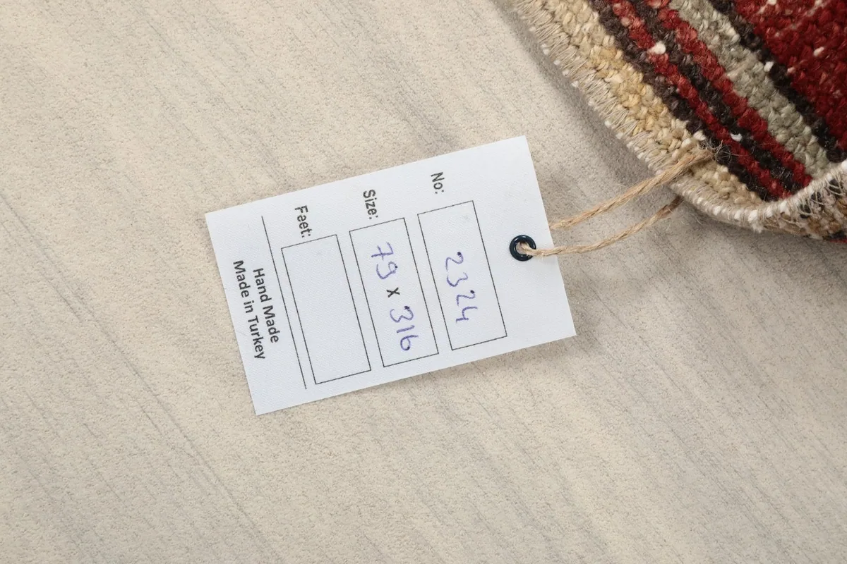 Close-up of the rug's product tag showing the dimensions in centimeters and 'Hand Made in Turkey'.
