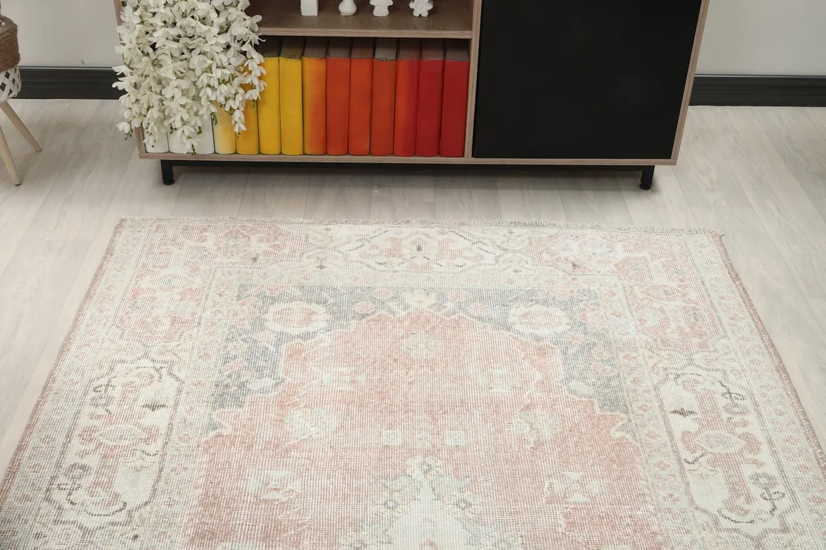 Overhead view focusing on one end of the rug, showing the faded field and border designs.