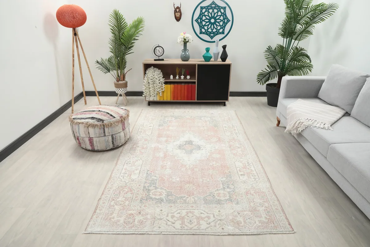 Vintage Anatolian rug with rose and gray tones displayed in a bright living room setting.