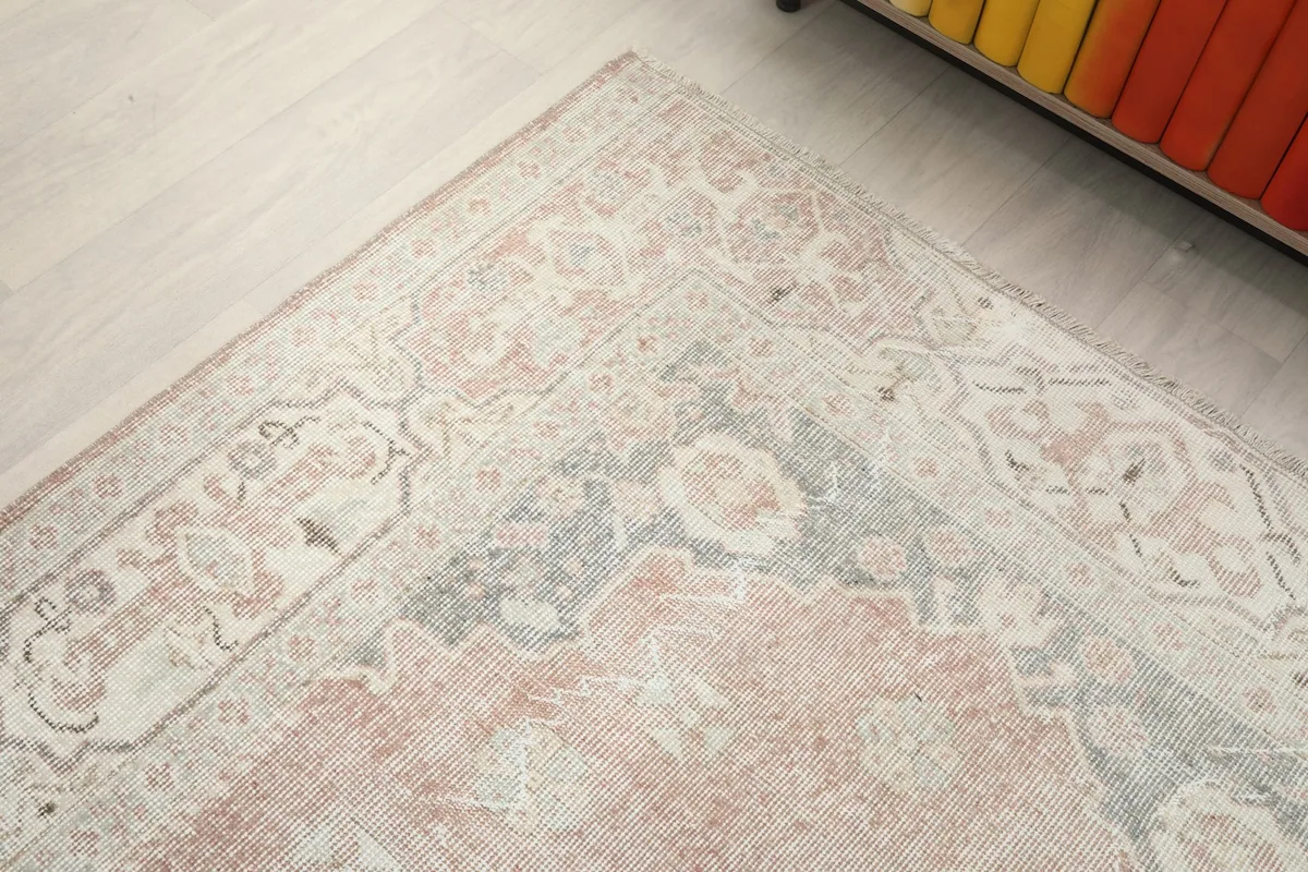 Corner detail of the rug, highlighting the interplay of rose, gray, and beige motifs.