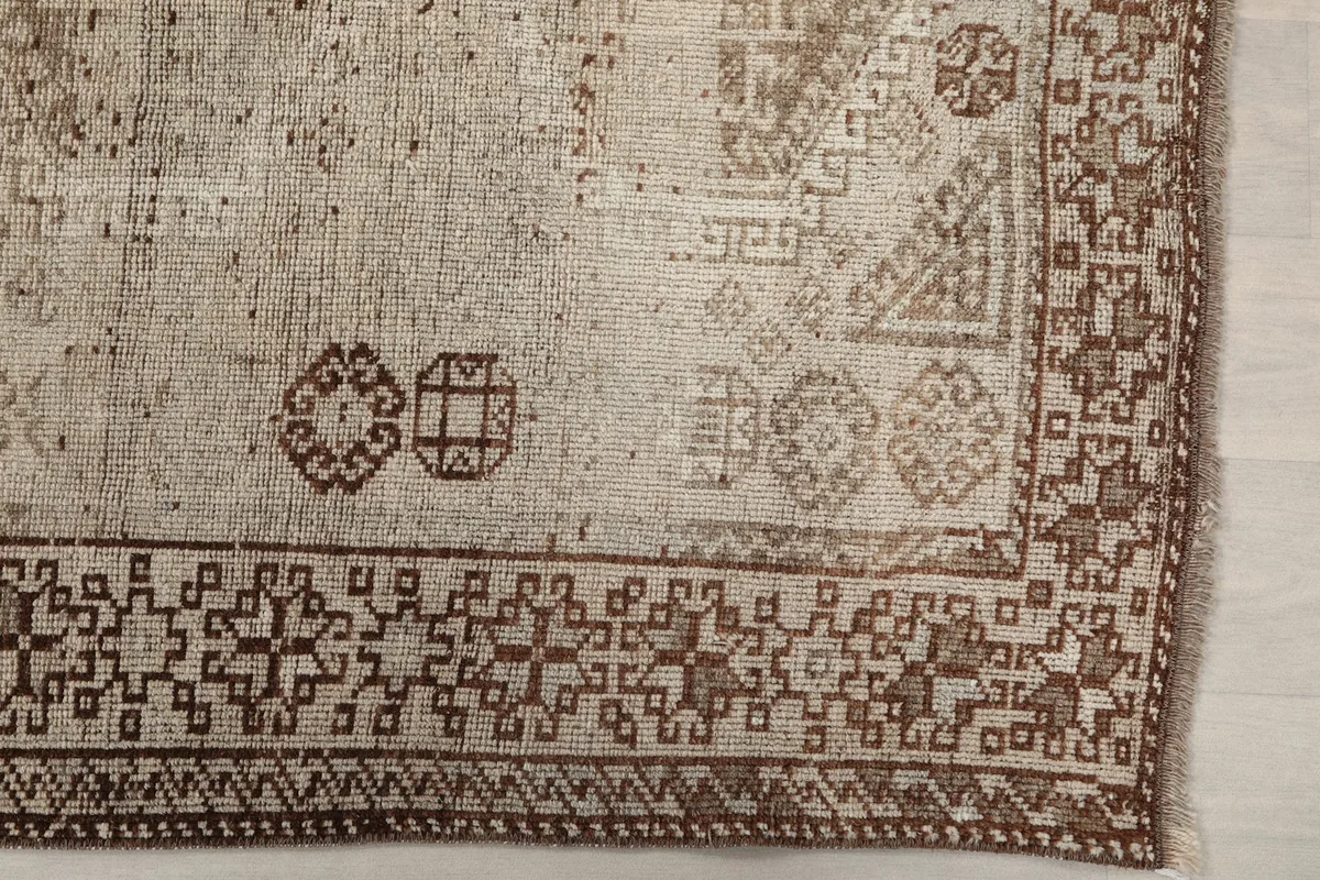 Detailed view of the rug's border and a corner, revealing the intricate brown geometric motifs.