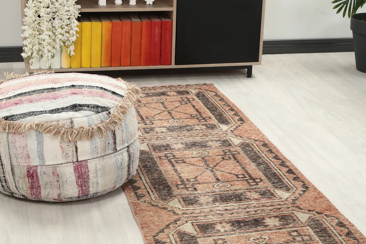 Close-up angle shot of the runner rug's pattern and texture next to a decorative ottoman.