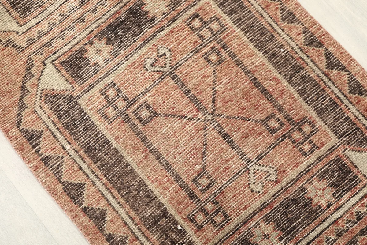 Close-up of a central medallion-like geometric motif within the rust field of the runner.
