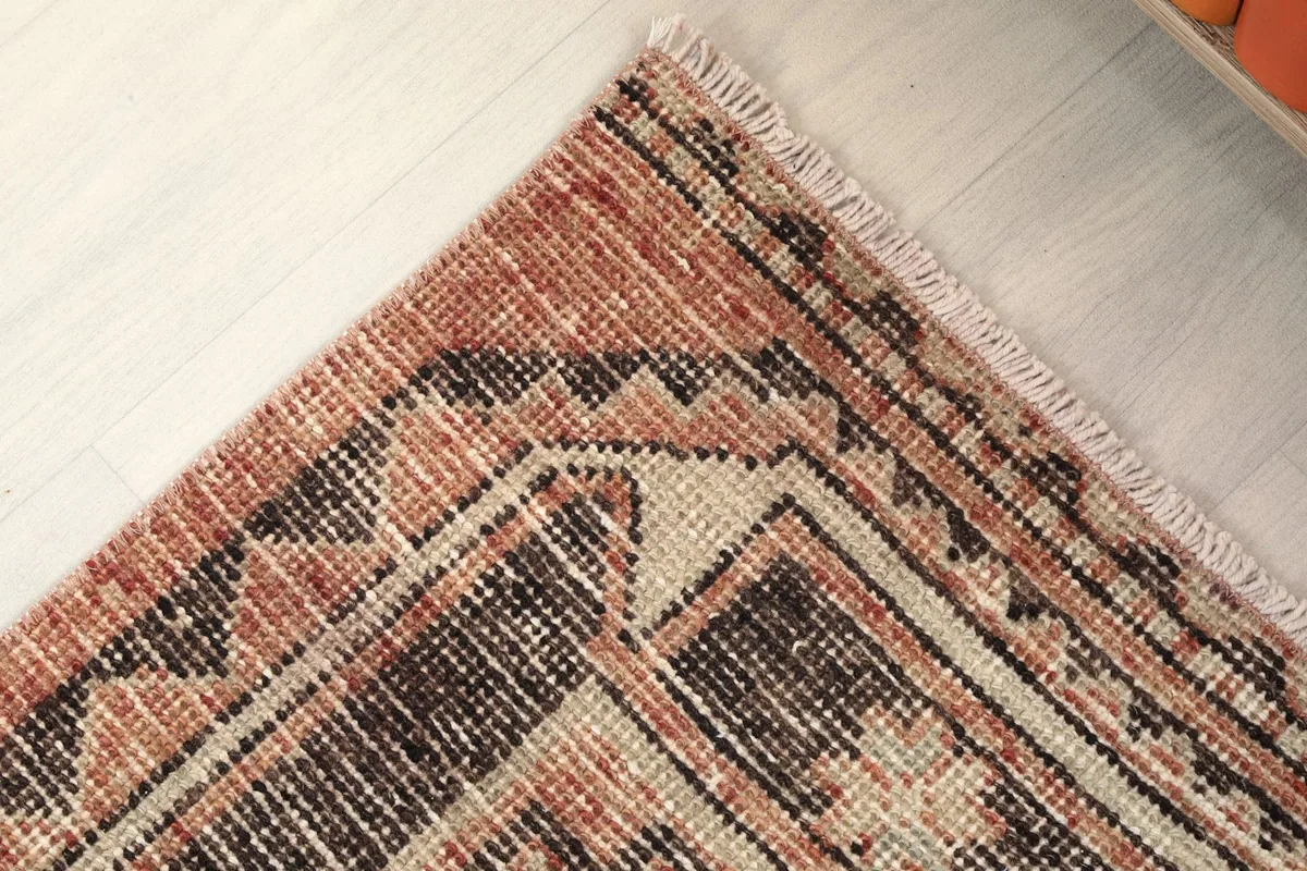 Detailed corner view of the rug's geometric border design and fringe.