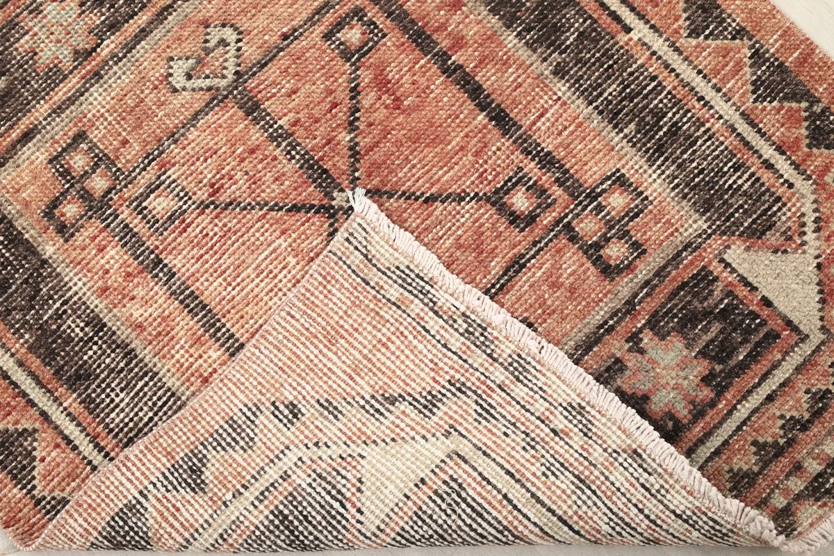 Corner of the rug folded back to show the cotton foundation and reverse side of the hand-knotting.