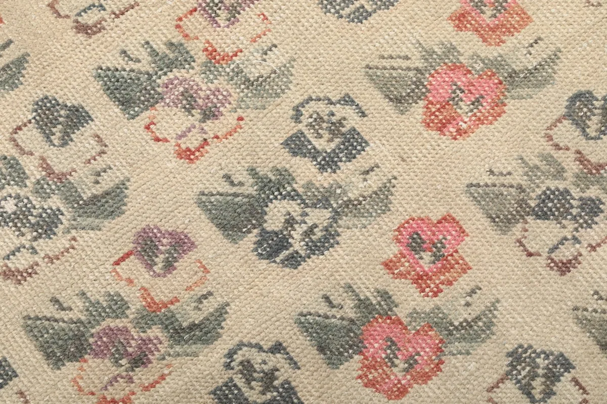 Close-up of the hand-knotted wool pile, showing individual floral patterns in pink, purple, and blue.