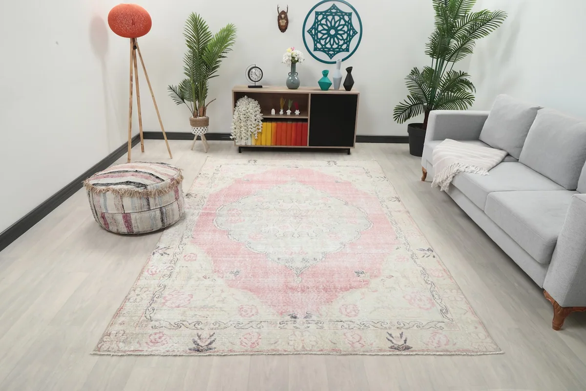 Vintage pink and ivory rug showcased in a modern living room setting with a gray sofa.
