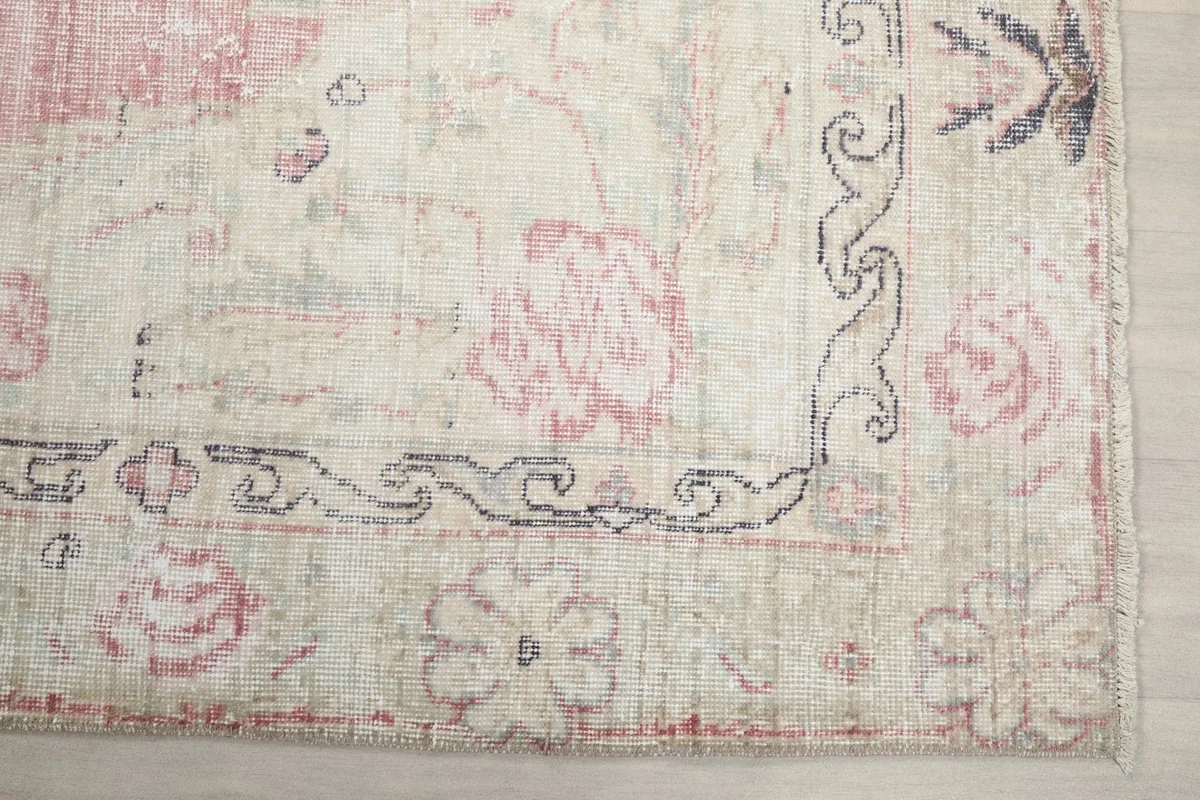 Detail of the rug's ivory border with floral motifs and subtle gray accents.