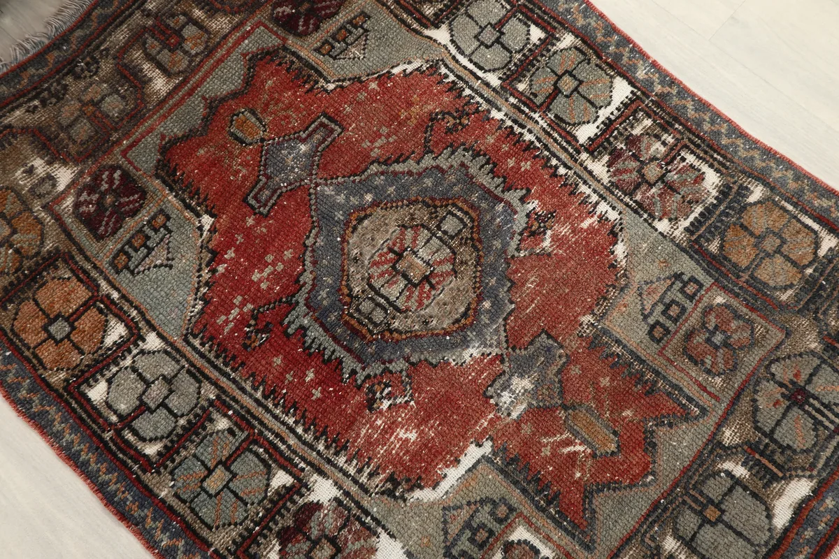 Angled view of the Faded Red Tribal Geometric Rug, emphasizing the faded red and gray tones.