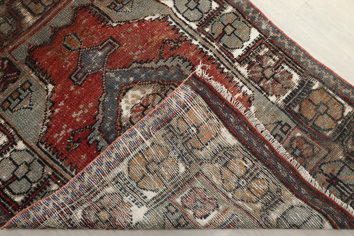 Faded Red Tribal Geometric Rug folded to show the flexibility and reverse side of the rug.