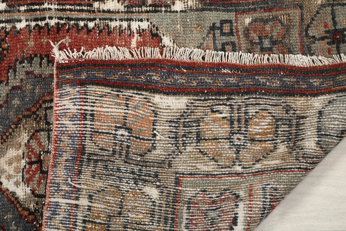 Close-up of the Faded Red Tribal Geometric Rug's backside and fringe, revealing hand-knotted construction.