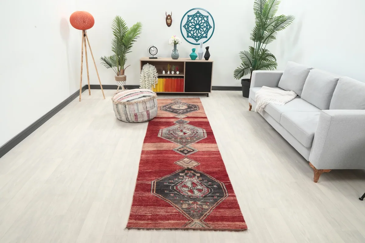Vintage Anatolian runner rug displayed in a modern living room setting with a light gray sofa and plants.