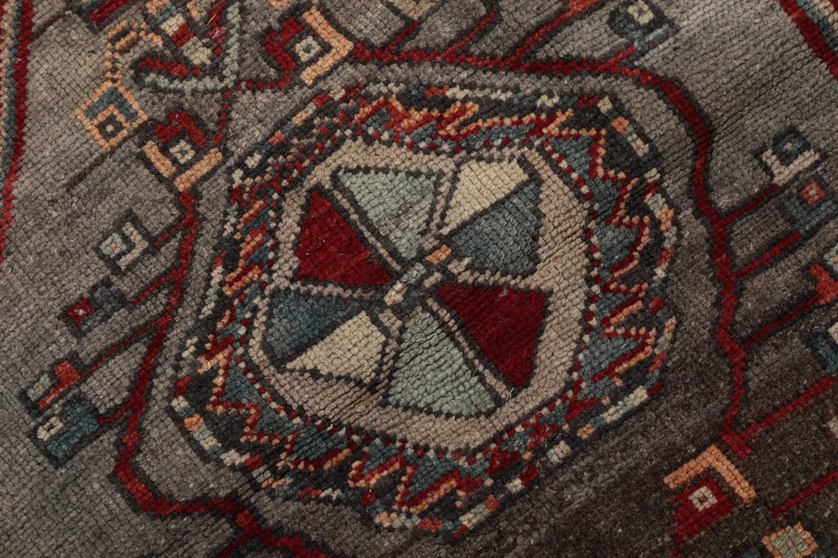 Very close-up shot of the intricate patterns and colors within a geometric medallion, showing wool texture.