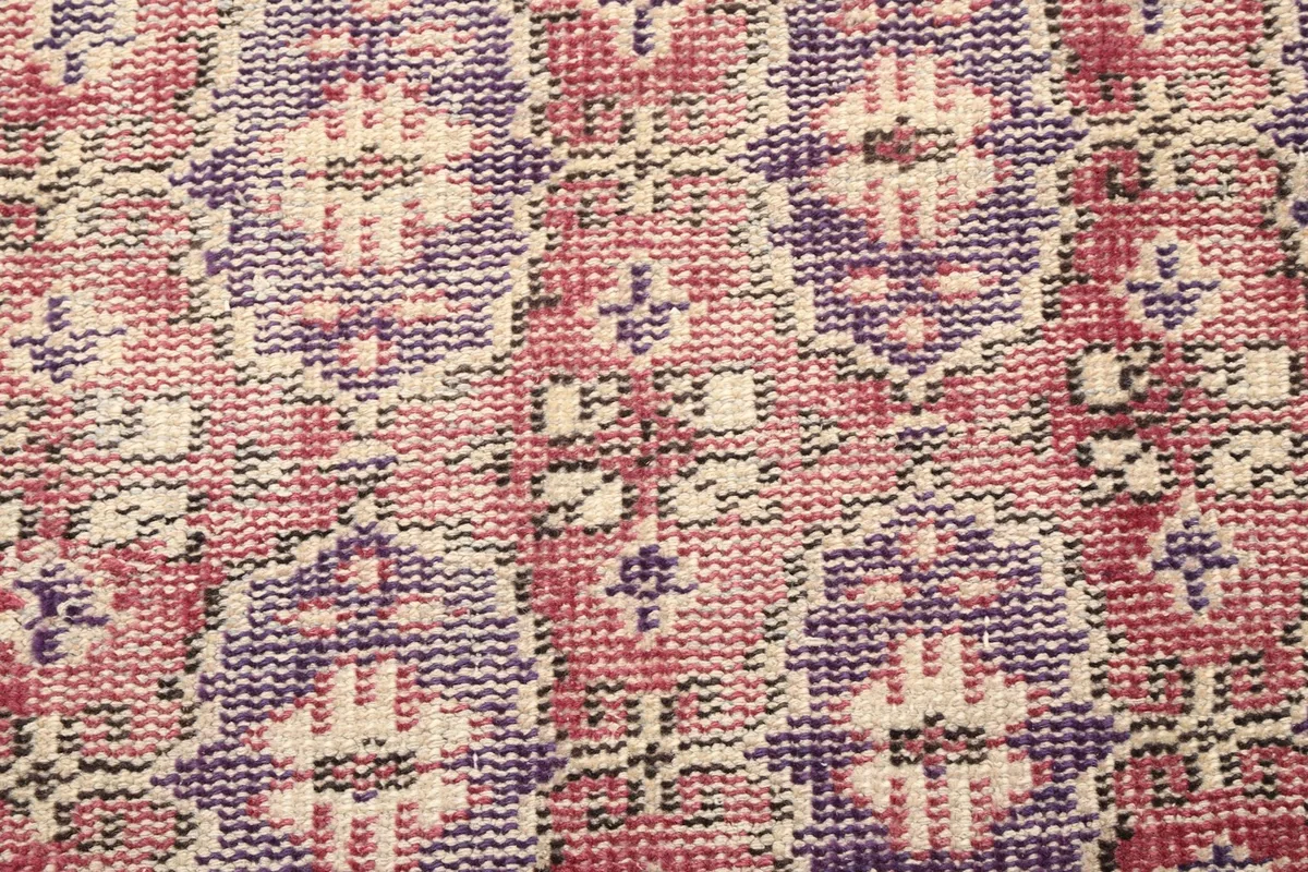 Extreme close-up of the hand-knotted wool pile and intricate purple patterns