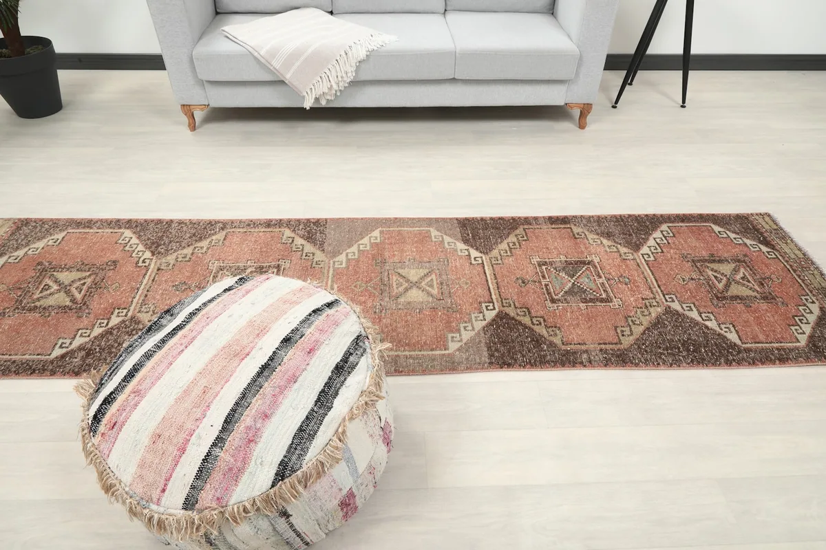 Runner rug in a room, viewed from above, with a sofa and ottoman