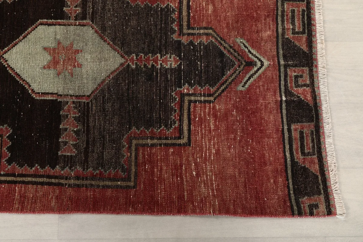Detailed view of the rust field and black geometric border design of the vintage runner